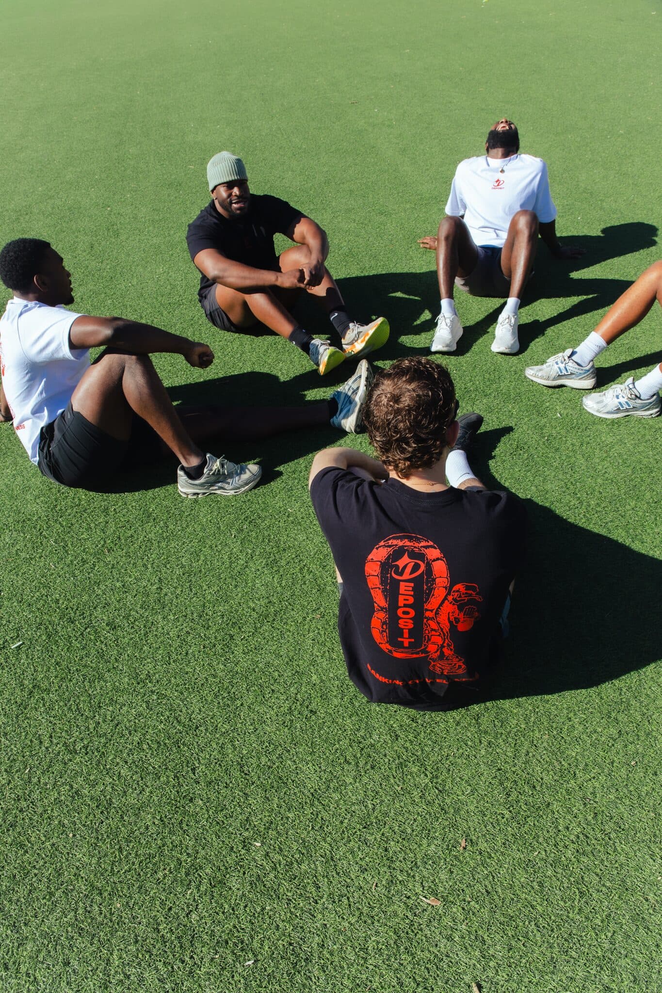 Group sitting on turf, candid and laughing.