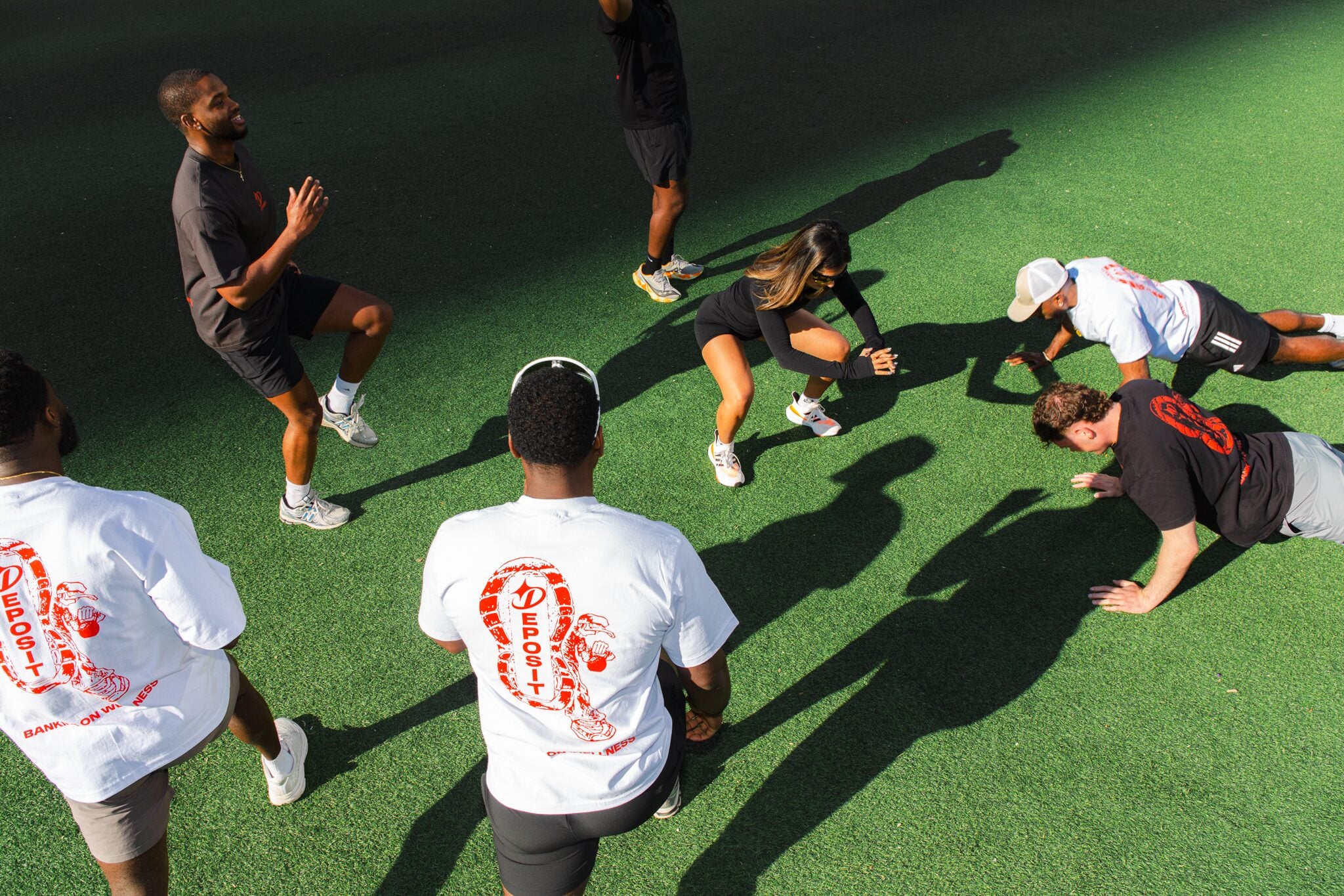 Group of people in a warmup circle on turf.
